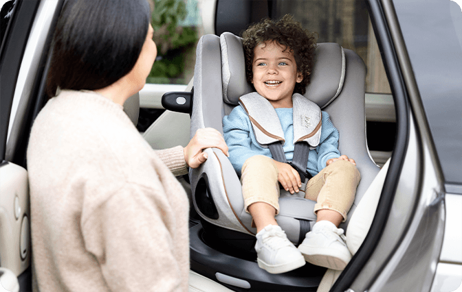 Mom spinning older toddler to rearfacing position in a Joie i-Harbour car seat.